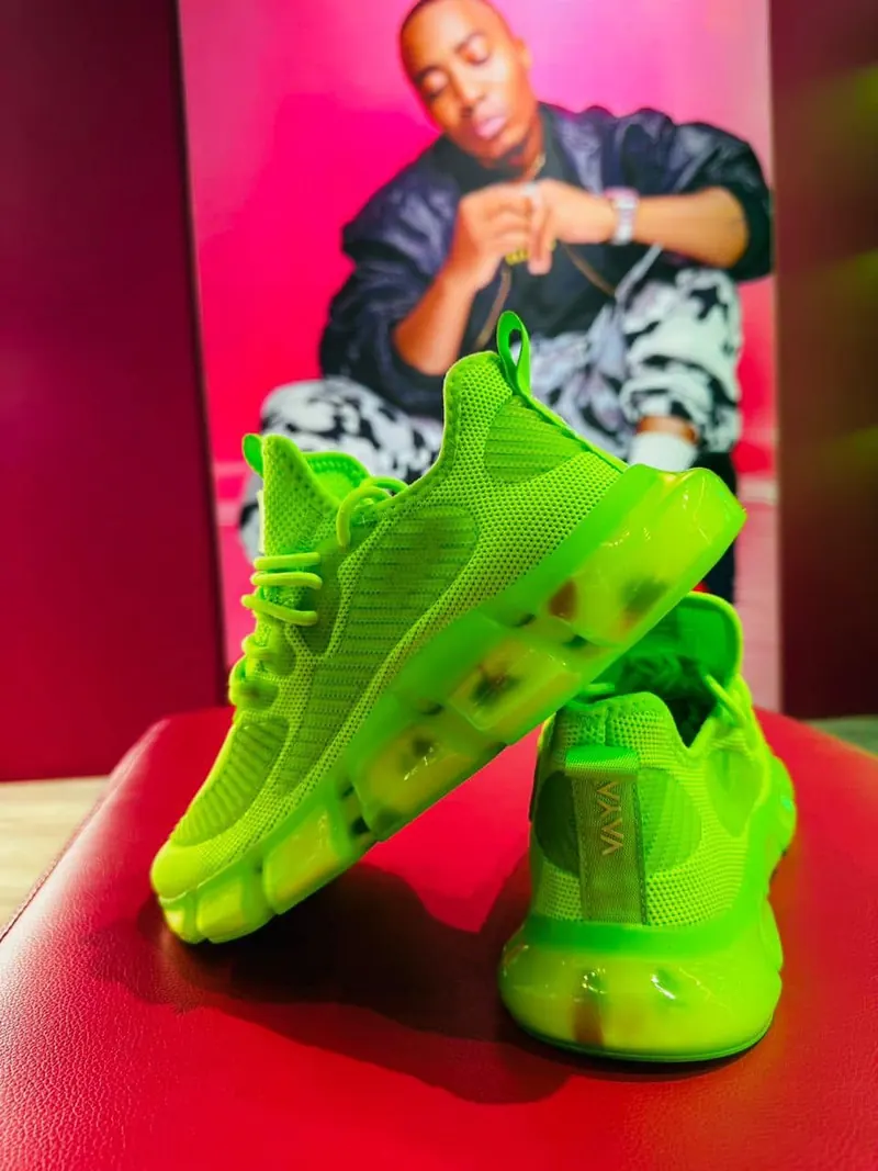 A VAYA wearer holding up a pair of bright Lime sneakers