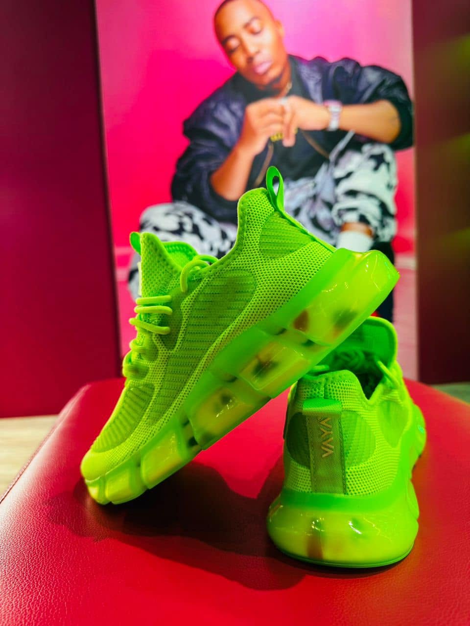 A VAYA wearer holding up a pair of bright Lime sneakers