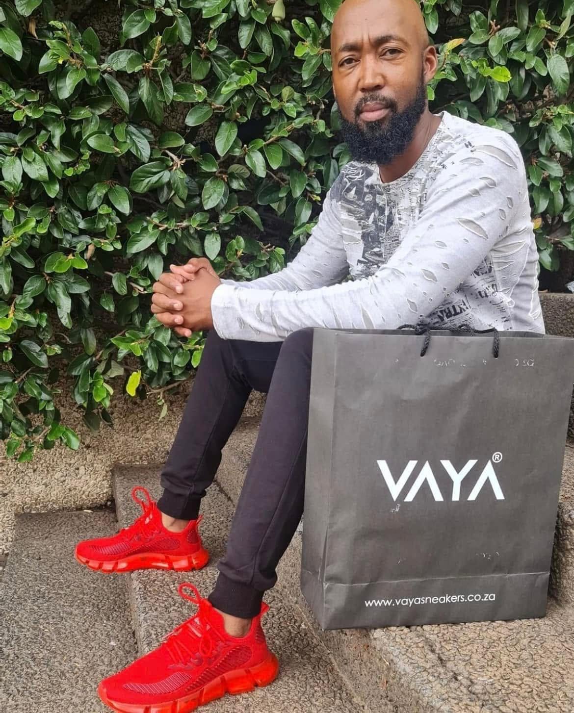 VAYA Red sneakers worn with a grey jacket and a VAYA shopping bag